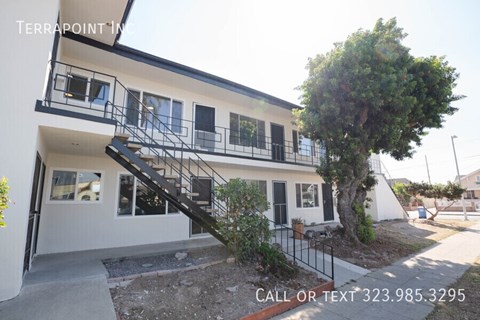 A white two-story building with a black metal staircase.