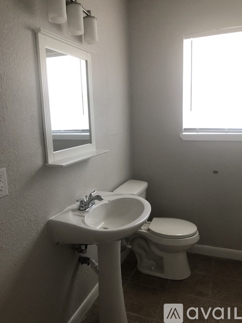 A bathroom with a toilet, sink, and window.
