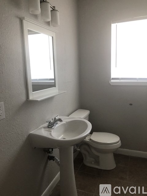 A bathroom with a toilet, sink, and window.