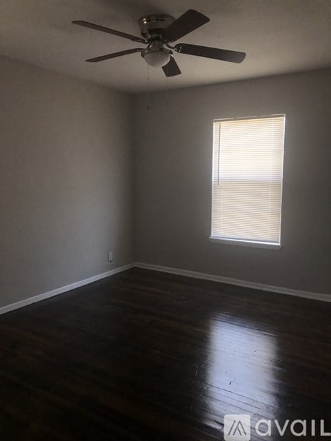 A room with a ceiling fan and a window with blinds.