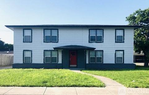 A white house with a red door and a grey front yard.