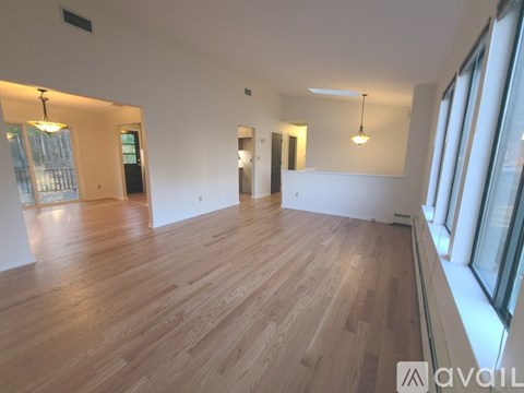 A spacious room with wooden flooring and large windows.