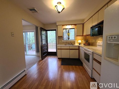 A kitchen with white cabinets and a black mat on the floor.
