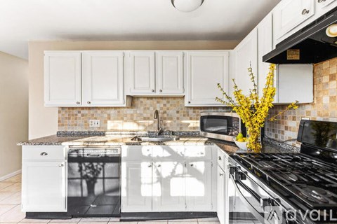 A kitchen with white cabinets and black appliances.