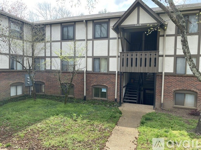 A building with a balcony and a tree in front of it.