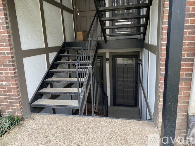 A staircase with a black railing and steps leading to a door.
