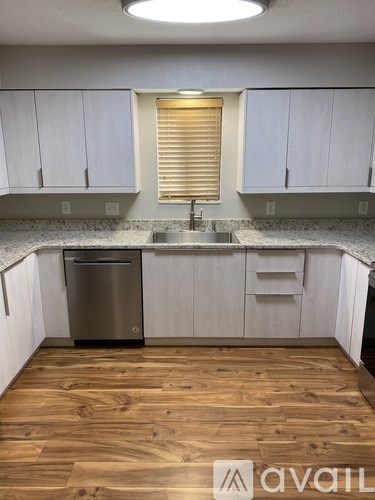 A kitchen with wooden floors and white cabinets.