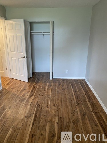 A room with a white door and a white wall with a wooden floor.