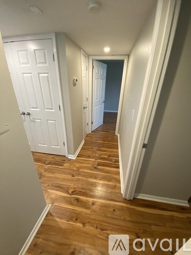 A hallway with wood floors and white walls.