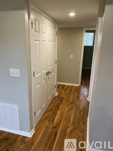 A hallway with a white door and wooden floors.