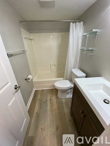 A white bathroom with a toilet, sink and shower.