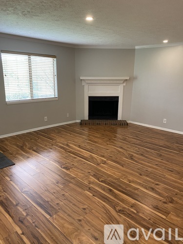 A room with wooden flooring and a fireplace.