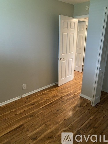 A room with a white door and wooden flooring.