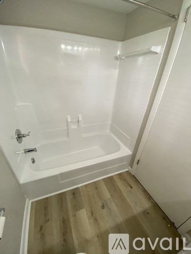 A white bathroom with a tub and wooden floors.