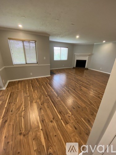 A spacious room with wooden flooring and a fireplace.