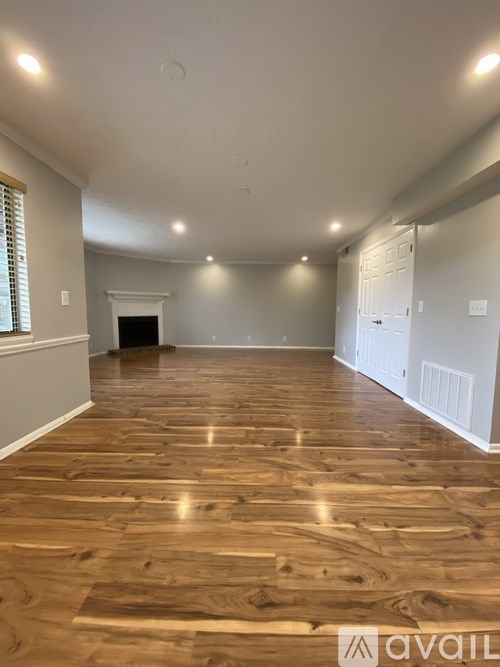 A spacious room with wooden flooring and white walls.