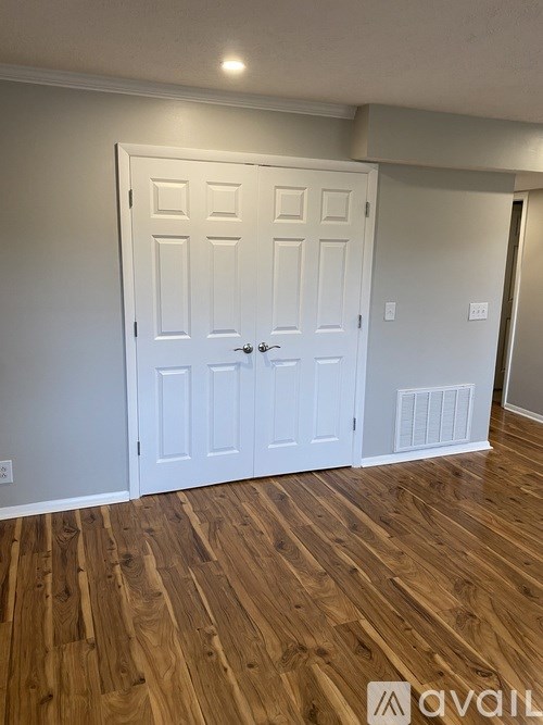 A white door with a black handle is in a room with wooden floors.