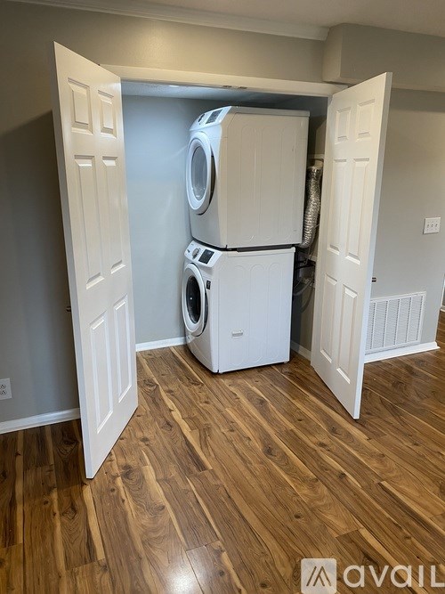 A stack of white washing machines in a room with wooden floors.