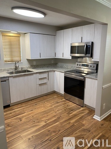 A kitchen with wooden floors and white cabinets.