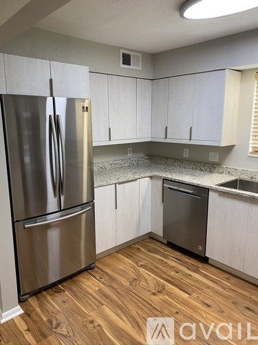 A kitchen with a stainless steel refrigerator and wooden flooring.