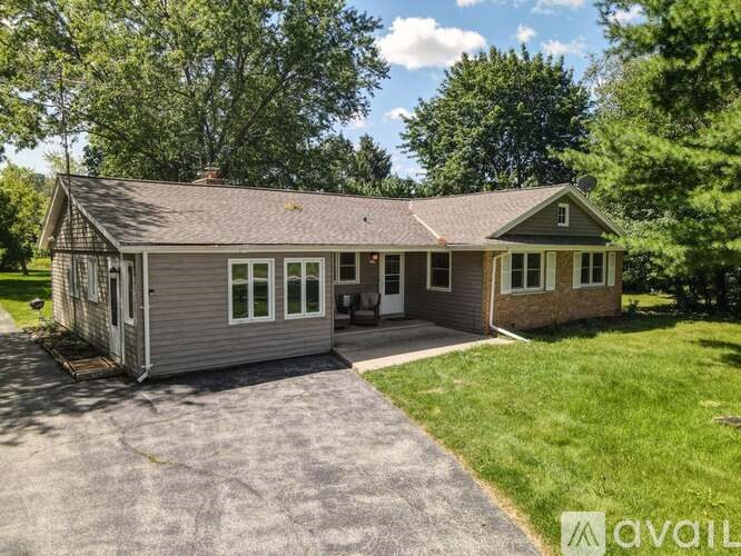 A house with a grey roof and a brown garage door is for sale.