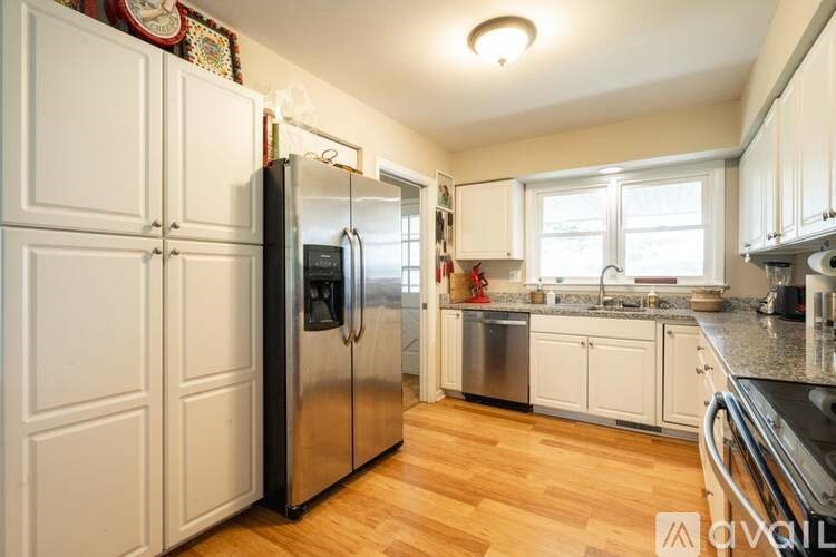 A kitchen with a refrigerator, sink, and cabinets.