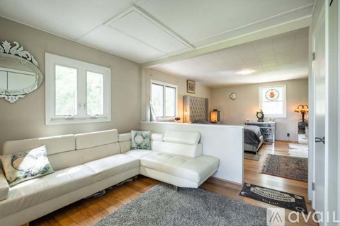 A living room with a white couch and a mirror on the wall.