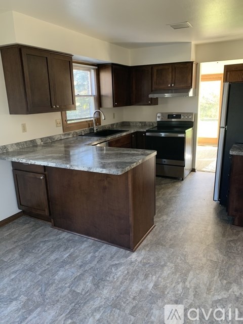 A kitchen with dark wood cabinets and a granite countertop.