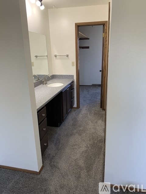 A bathroom with a sink, mirror, and a door.