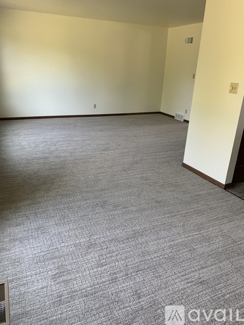 A room with a carpeted floor and a wall with a switch.