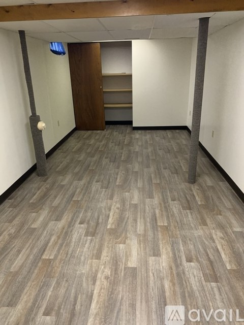 A hallway with wood flooring and a white wall.