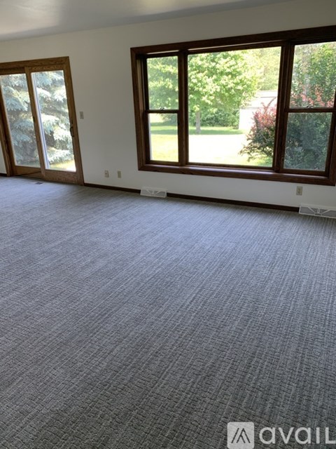 A room with a carpeted floor and a large window.