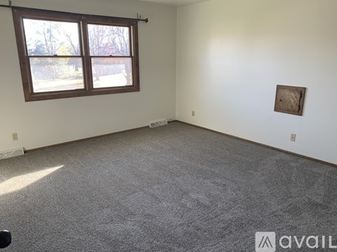 A room with a carpeted floor, a window, and a picture on the wall.
