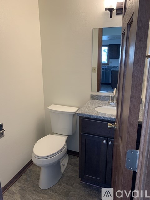 A bathroom with a toilet, sink, and mirror.