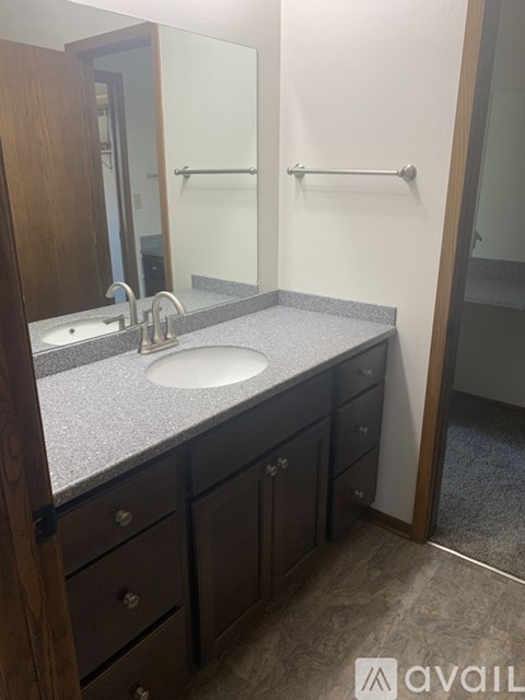 A bathroom with a sink, mirror, and wooden cabinets.