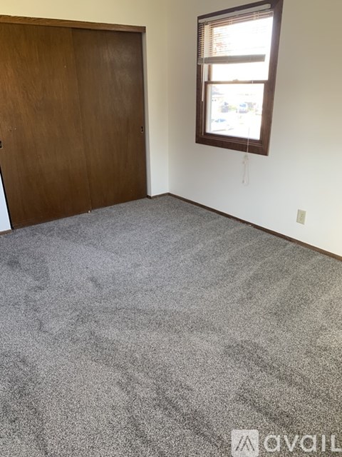 A room with a carpeted floor and a wooden door.