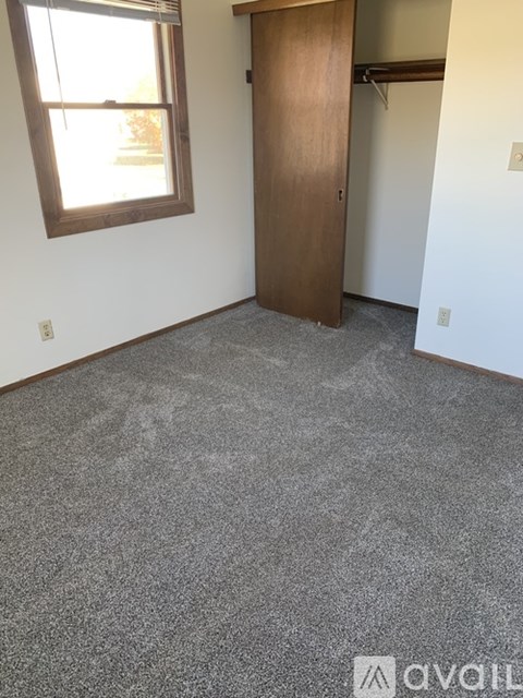 A room with a carpeted floor and a wooden door.