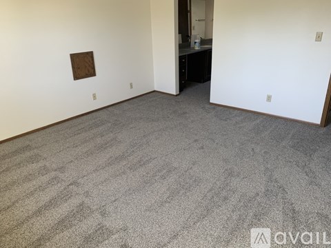 A carpeted room with a desk and a picture on the wall.