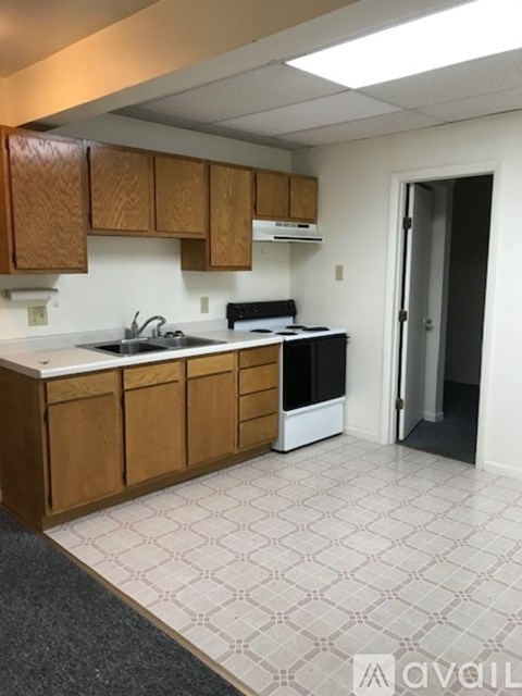 A kitchen with wooden cabinets and a white tile floor.