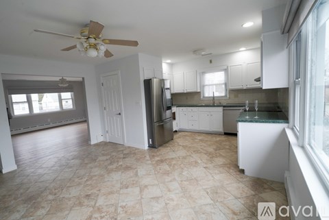 A kitchen with a fan on the ceiling and a tiled floor.