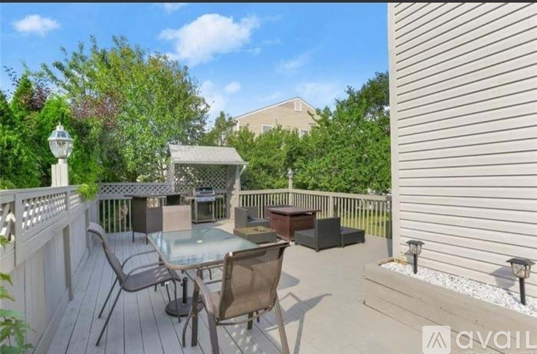 A patio with a glass table surrounded by chairs and a white fence.