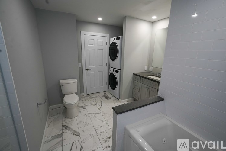 A bathroom with a toilet, washing machine, and a bathtub.