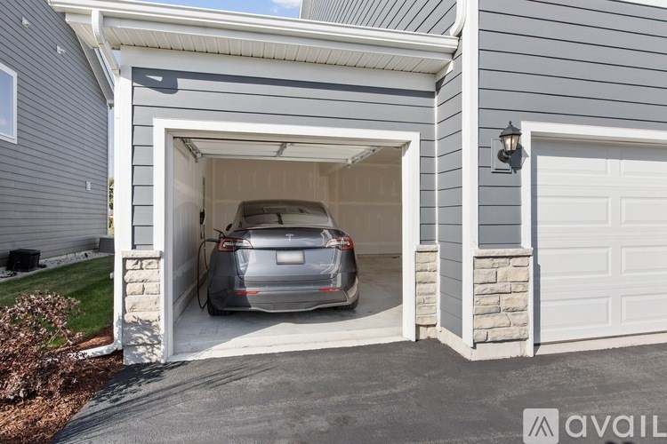 A silver car is parked in a garage attached to a house.