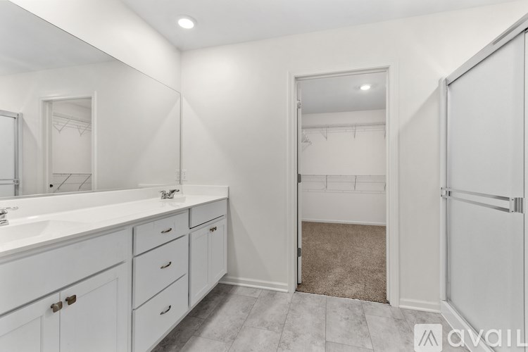 A bathroom with white cabinets and a walk-in closet.