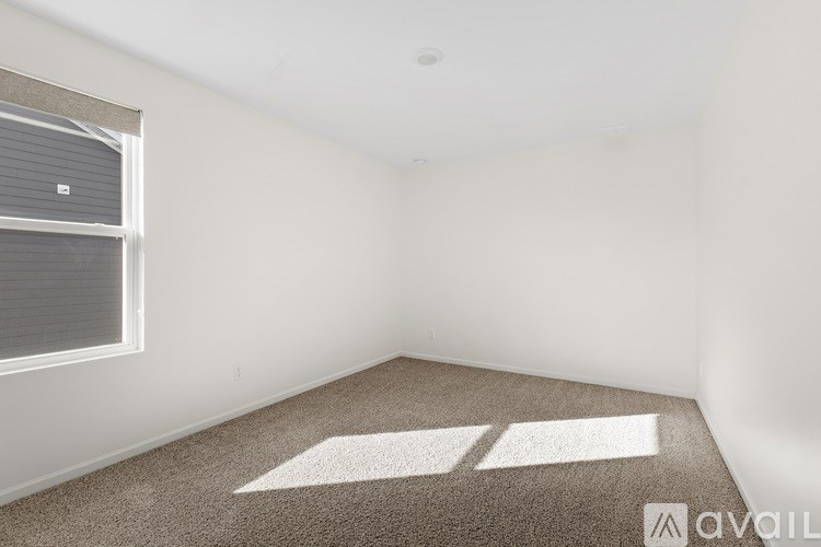 A room with a carpeted floor and a window with blinds.