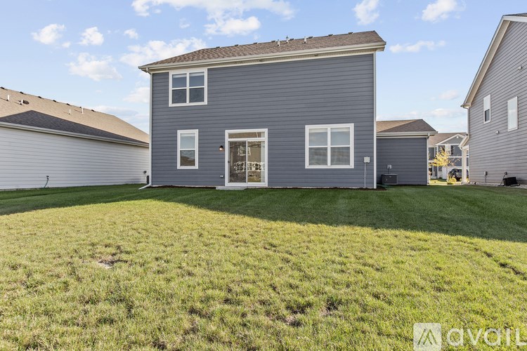A house with a grey exterior and a brown roof is surrounded by a grassy area.