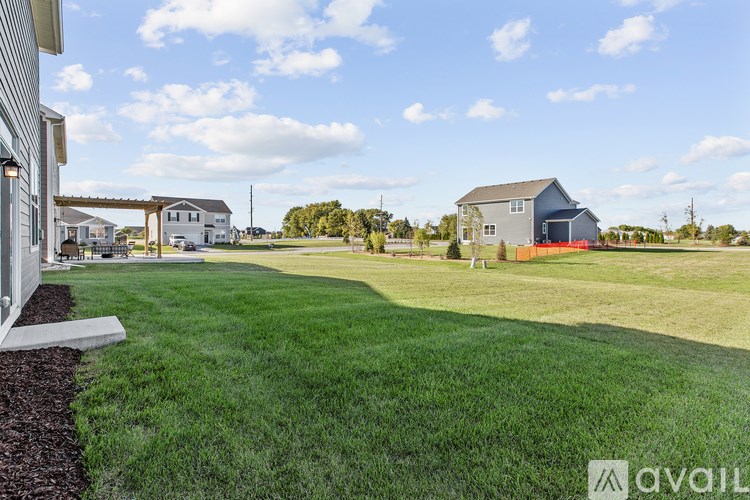 A grassy field with a house and a shed in the background.