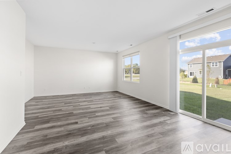 A spacious room with wooden flooring and large windows.