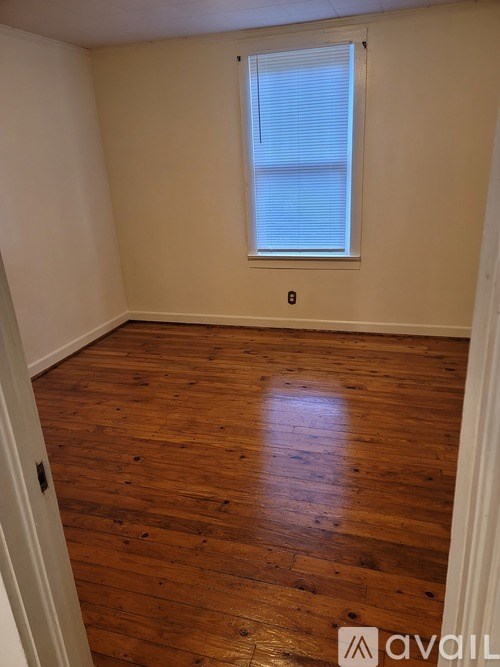 A room with wooden floors and a window with blinds.