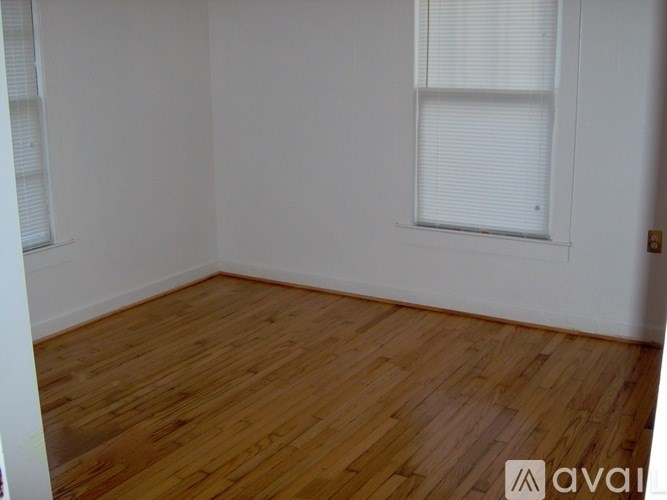 A room with wooden flooring and a window with blinds.